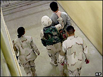 A US military intelligence officer leads an Iraqi prisoner at Abu Ghraib